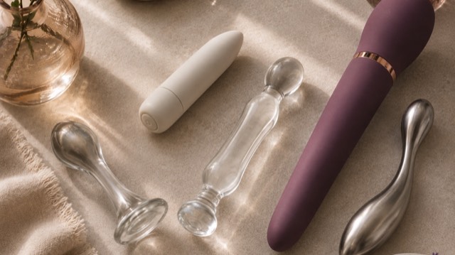 Silicone, glass and stainless-steel pleasure products arranged together in warm natural light