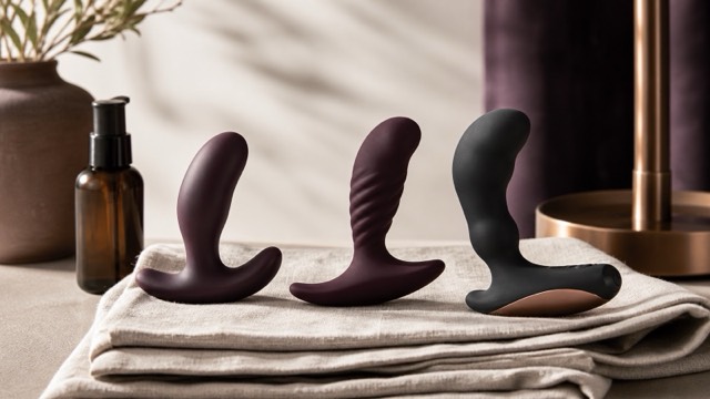 Three compact prostate massager shapes with flared retrieval bases arranged beside water-based lubricant