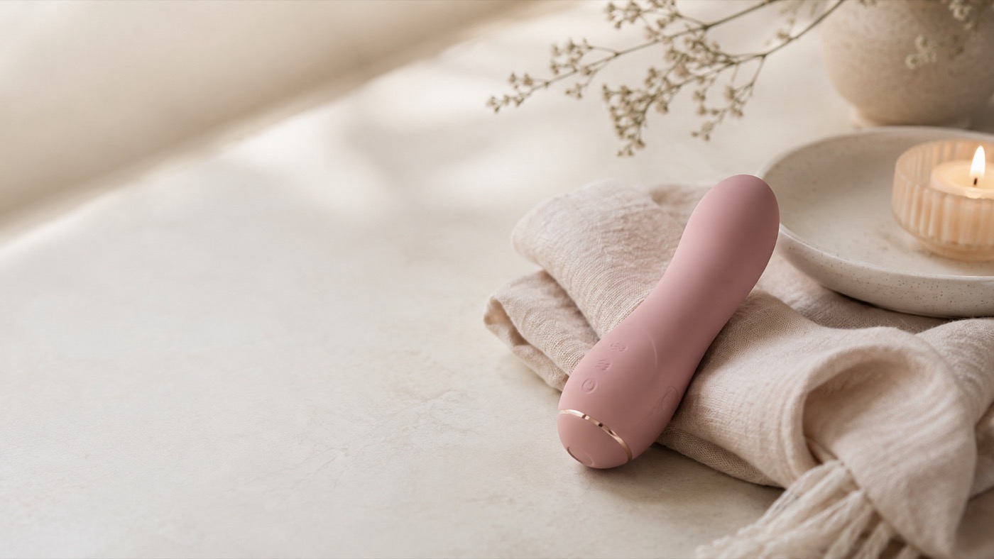 A pink vibrator resting on folded linen in warm natural light